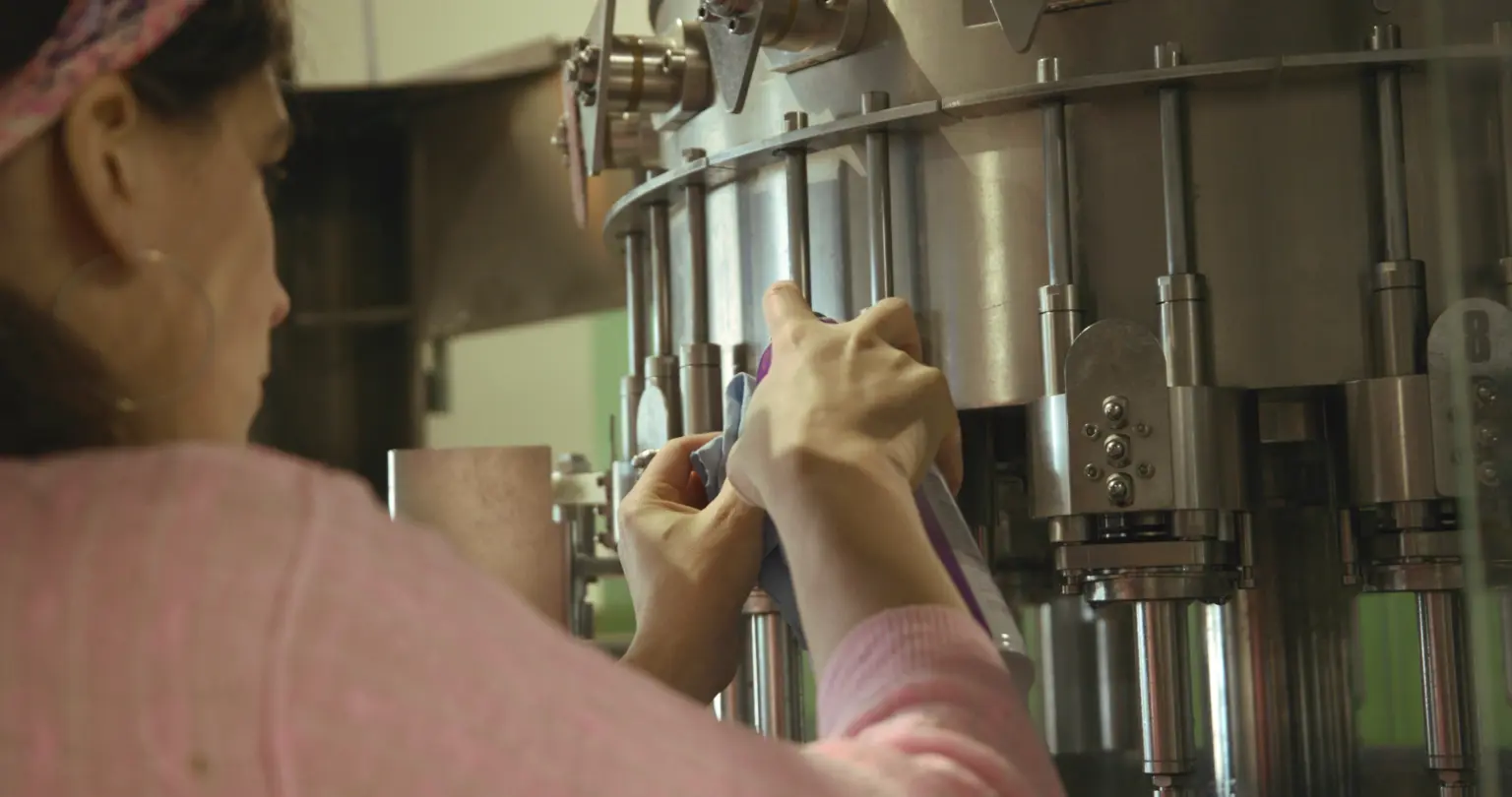 Worker cleaning bottling equipment